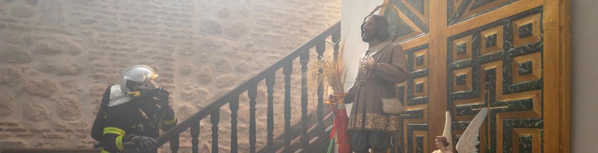 Bombero subiendo las escaleras en el interior de una iglesia, en primer plano una pieza