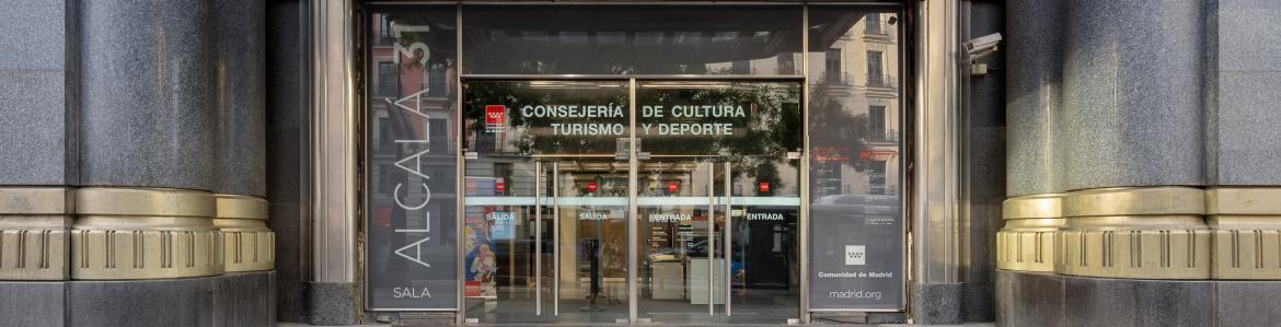 Vista de una fachada acristalada con escaleras y marquesina