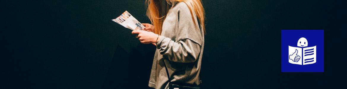 Mujer joven de perfil leyendo un folleto 