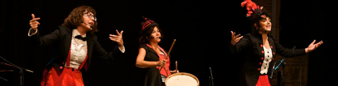 Fotografía de la compañía en escena, disfrazada de maestras de ceremonia tocando y cantando