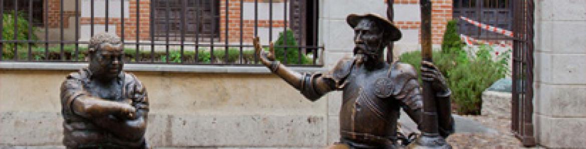 Estatuas en bronce de don Quijote y Sancho  sentados en un banco frente a la fachada principal del Museo Cervantes en Alcalá de Henares