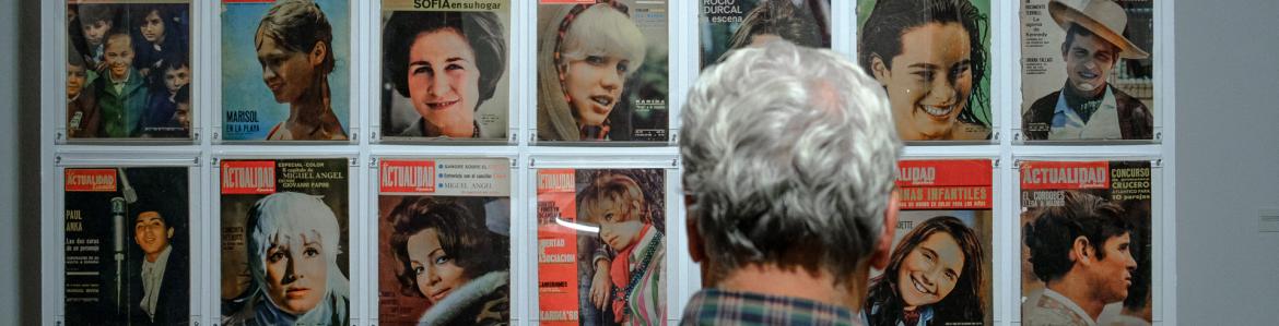 Hombre mirando portada de revistas expuestas en una pared