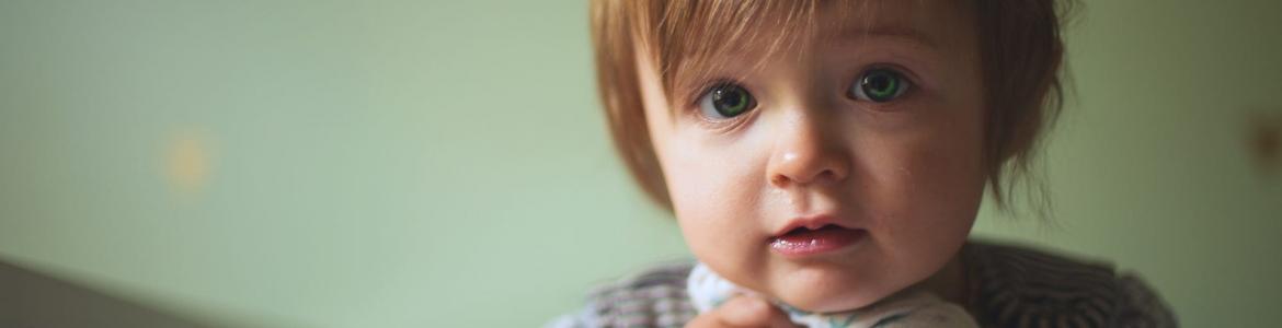 Niño de frente agarrado a muselina asomado a una barandilla Niño de frente agarrado a muselina asomado a una barandilla