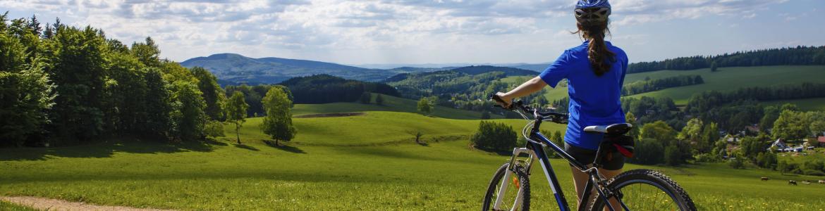 Ciclista de espaldas contemplando un paisaje verde