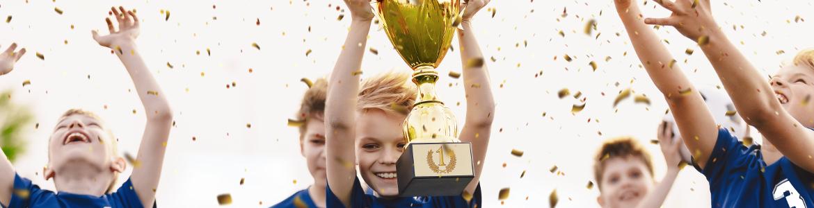 Niños contentos levantando trofeo