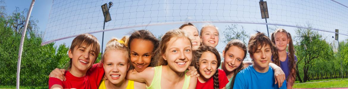 Niños sonrientes sentados en una cancha de voleibol