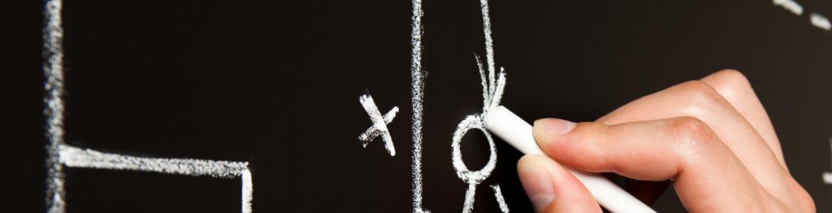 Una mano sujetando una tiza y escribiendo en una pizarra