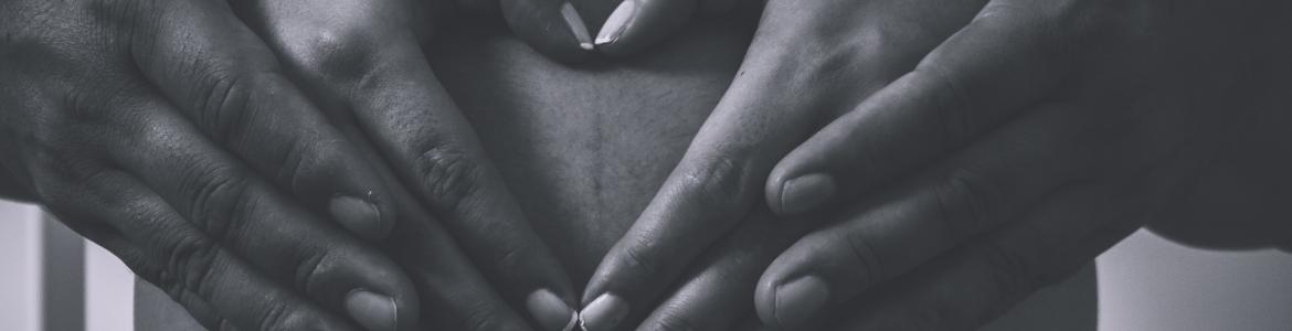 Una pareja con las manos enlazadas sobre el vientre de la mujer embarazada