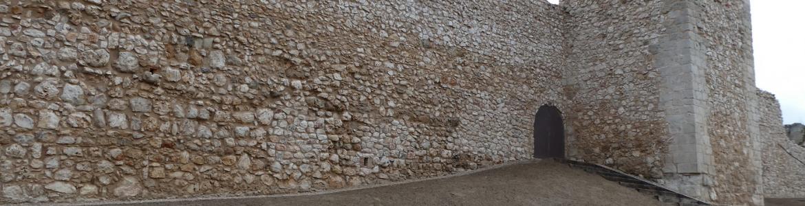 muralla de piedra con torre rectangular y puerta de acceso