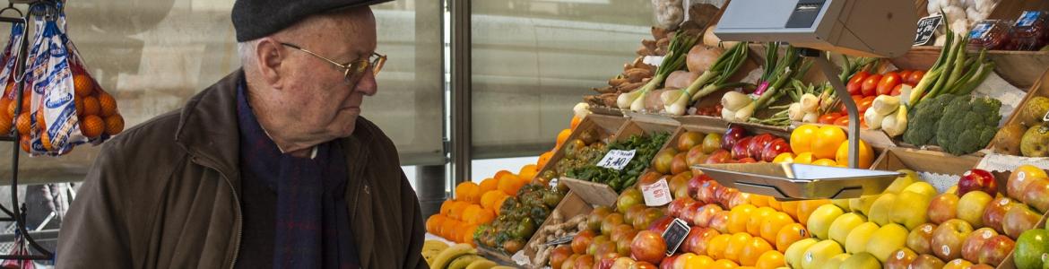 Señor mayor comprando en un puesto de fruta