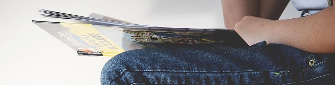 Joven sentada sobre libros y sujetando un libro en las manos