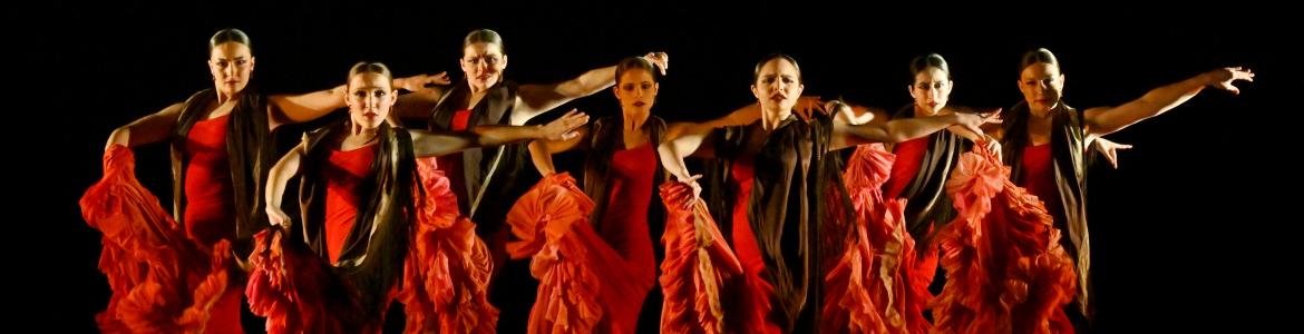 Bailarinas sobre un escenario con trajes rojos de flamenco