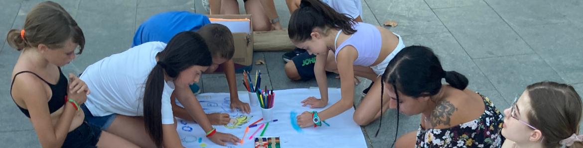 jóvenes pintando con colores en el suelo en un papel gigante
