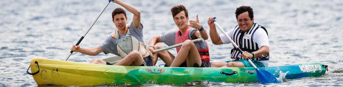 3 jóvenes remando en una piragua en un lago