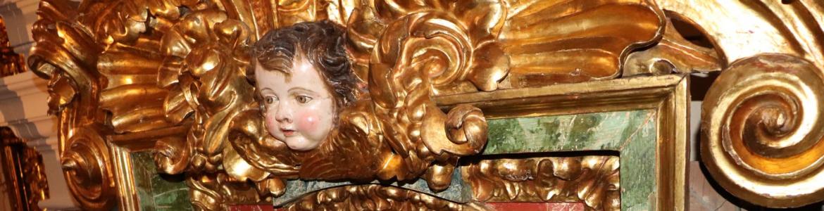 Detalle del Retablo de San Juan Bautista tras de su restauración imagen de un fragmento de retablo con una cabeza de ángel esculpida y una pintura insertada en marco decorado