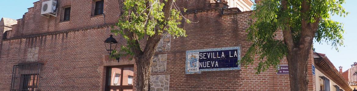 Fachada de edificio de ladrillo con cartel de azulejería de Sevilla la Nueva