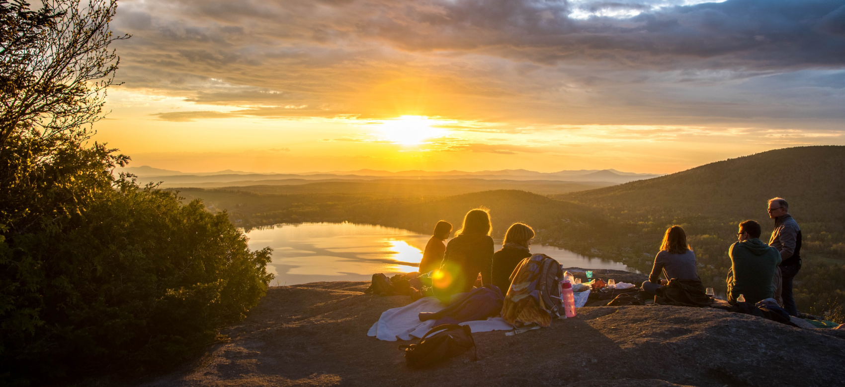 Un grupo de personas viendo el atardecer en un acantilado