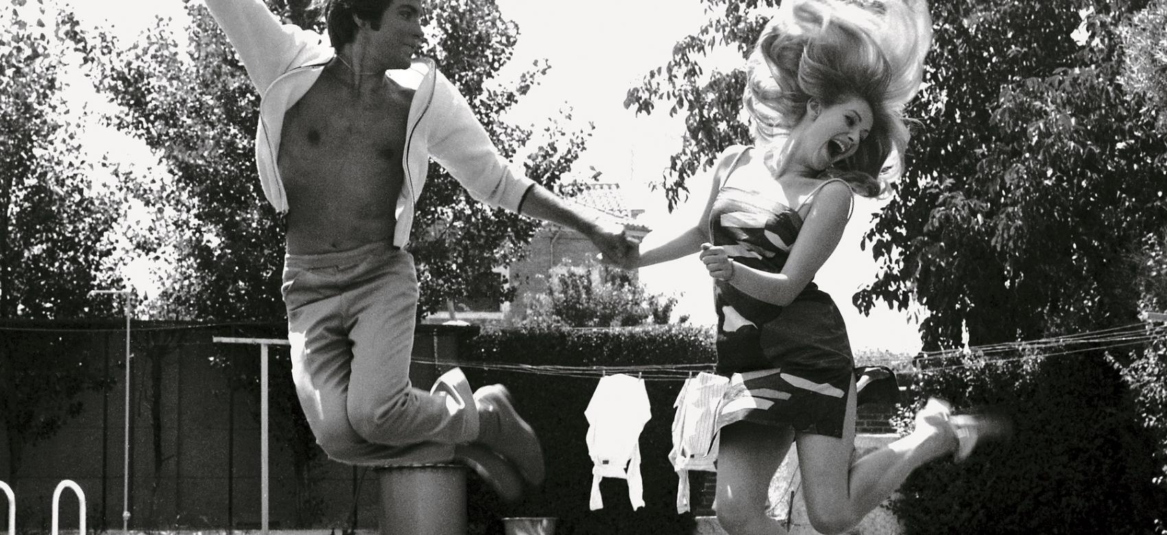 imagen de una pareja en un jardín saltando en el aire mientras se da de la mano