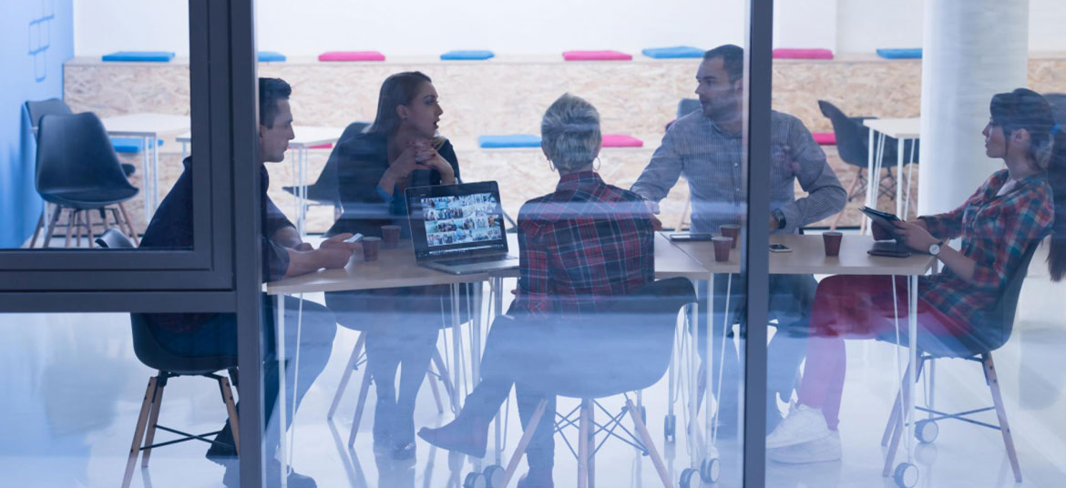 Cinco personas reunidas en torno a una mesa de trabajo