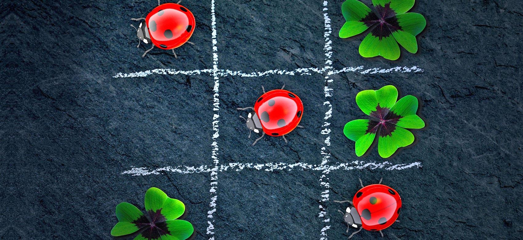 Tres en raya con mariquitas rojas brillantes y tréboles de cuatro hojas sobre un fondo de pizarra oscura