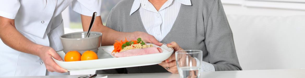 Mujer sirviendo comida a una mujer en una residencia de la tercera edad