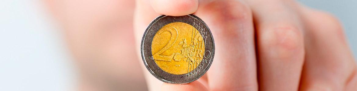 Tarifas del transporte público Imagen de moneda de dos euros entre los dedos.