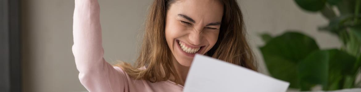 Becas para estudiantes universitarios Estudiante contenta leyendo una notificación