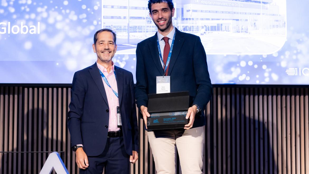 Dos hombres posando en el escenario el de la derecha con un premio en la mano