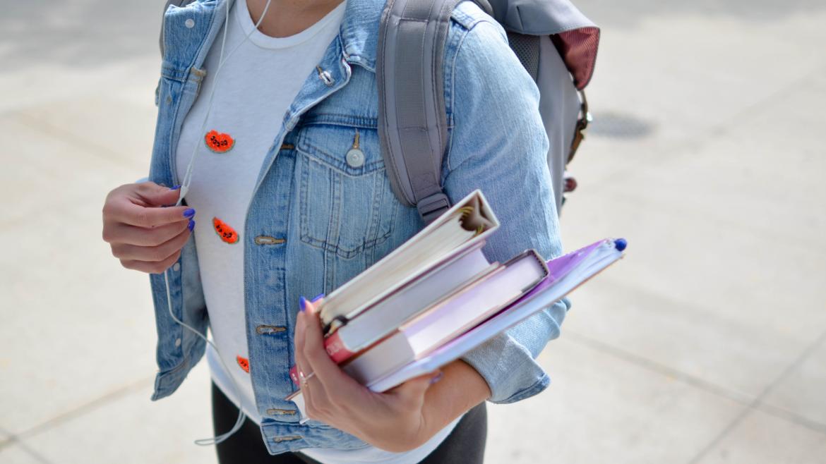 Estudiante con libros en la mano y mochila a la espalda