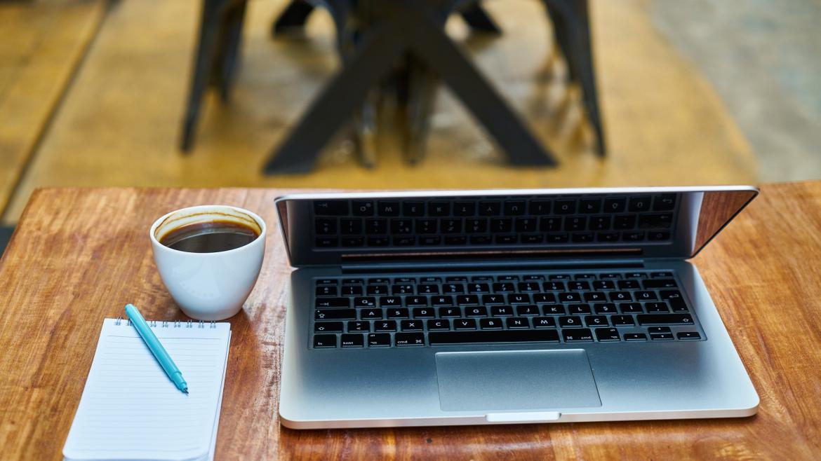 Ordenador, libreta y taza de café