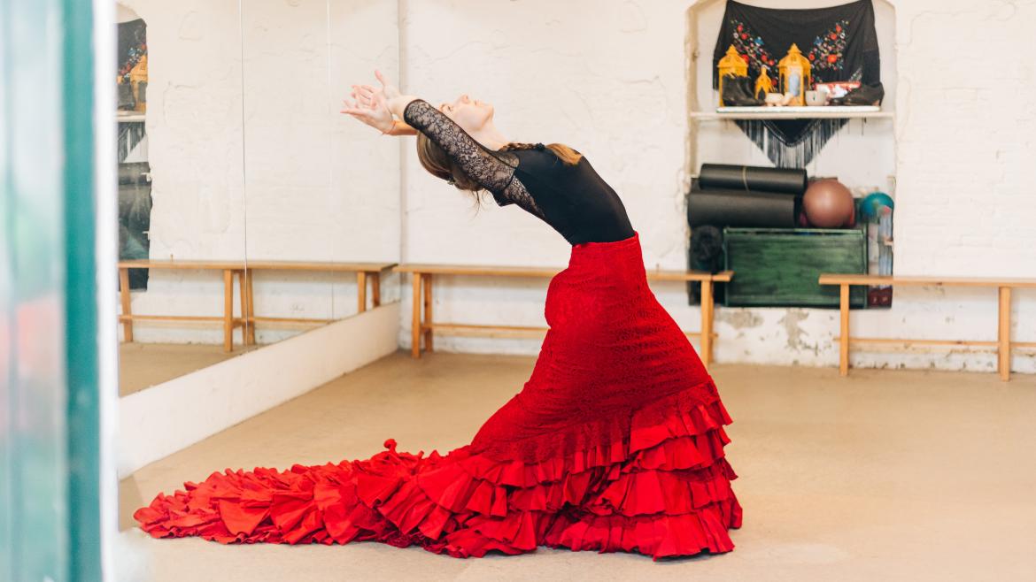 Una bailaora en su estudio con una bata de cola roja