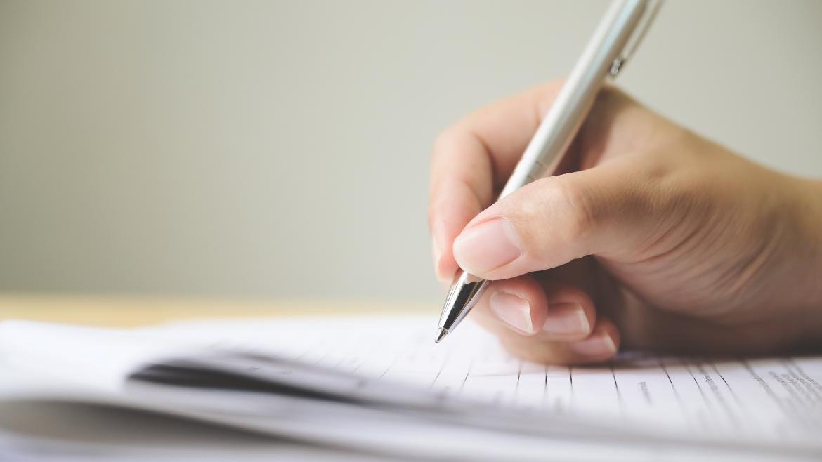 Mano con un bolígrafo firmando unos papeles