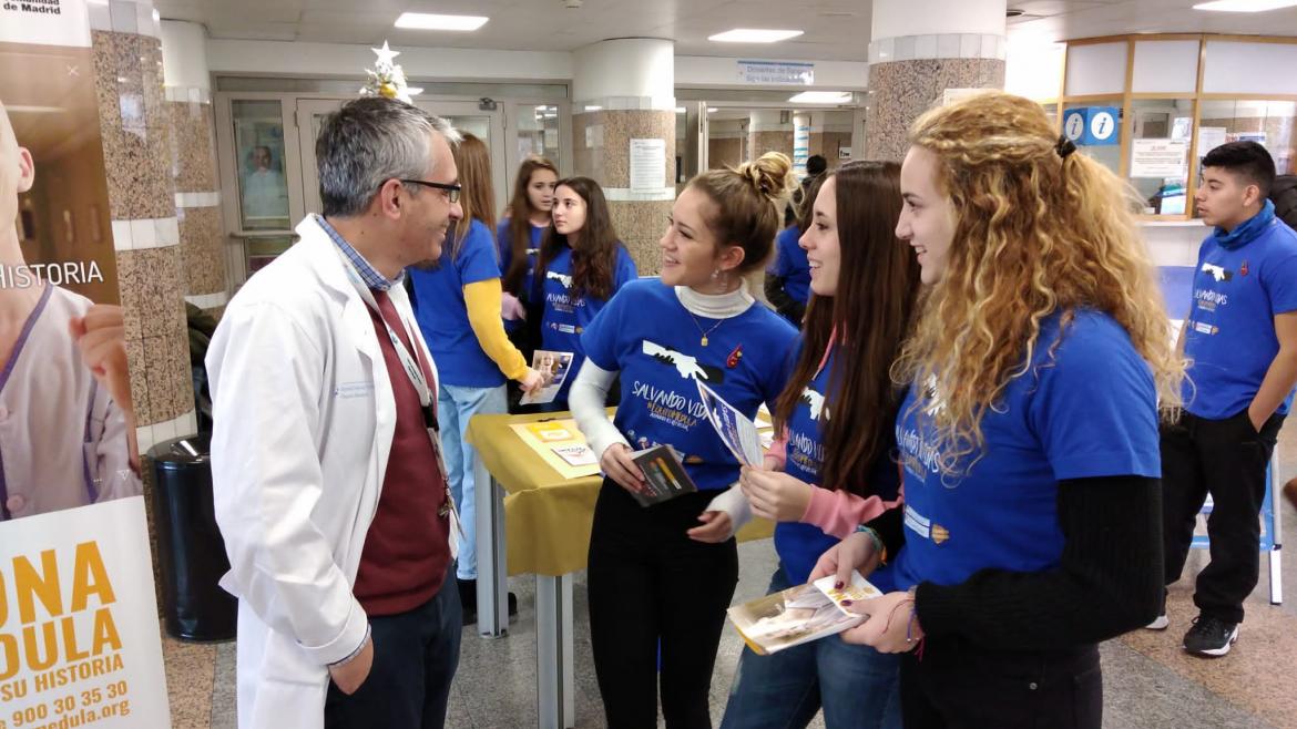 Alumnos con un profesional médico mientras pormocionan la donación de médula