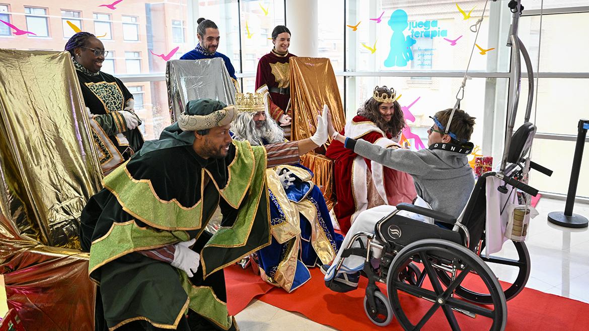 Los Reyes Magos visitan el Hospital Materno-Infantil Gregorio Marañón Un niño en silla de ruedas choca la mano con los Reyes Magos
