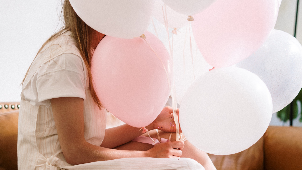 Imagen de una persona sentada con globos blancos y rosas