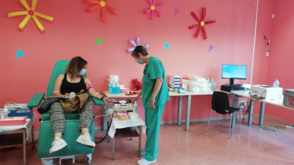 mujer donando sangre con una enfermera al lado