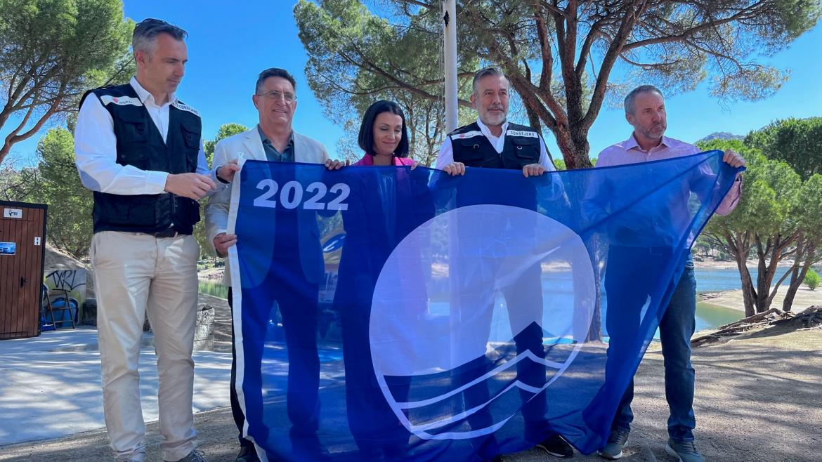 La Comunidad de Madrid activa el dispositivo estival para reforzar la seguridad en el pantano de San Juan El consejero Enrique López muestra la bandera azul en el Pantano de San Juan