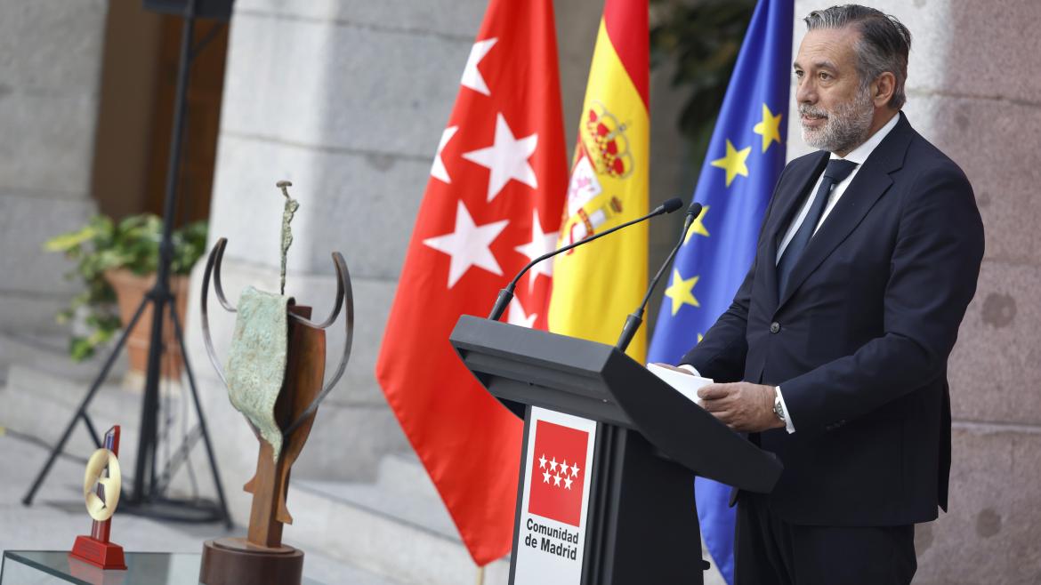 El consejero Enrique López interviene en el acto desde el atril con el trofeo al lado