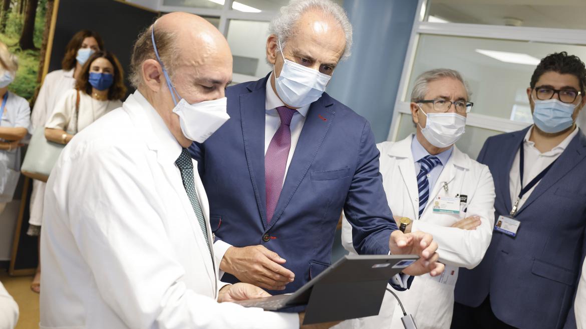 El consejero Enrique Ruiz Escudero observa una tablet mientras habla con un médico