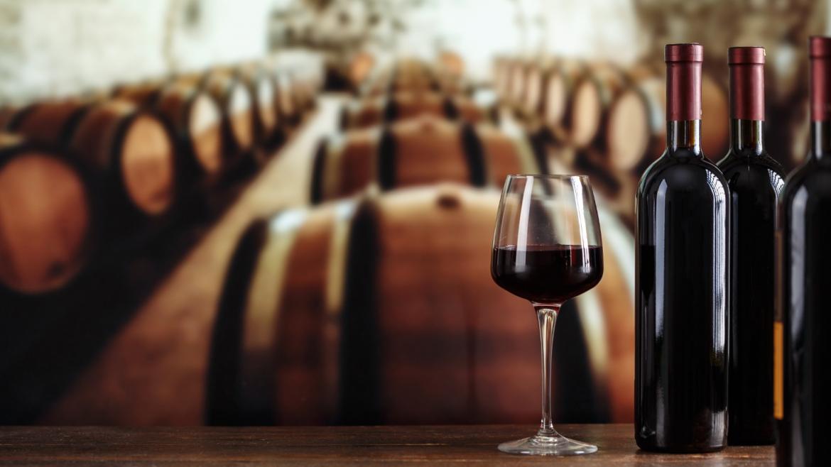 Copas de llenas de vino en una bodega con barricas de madera