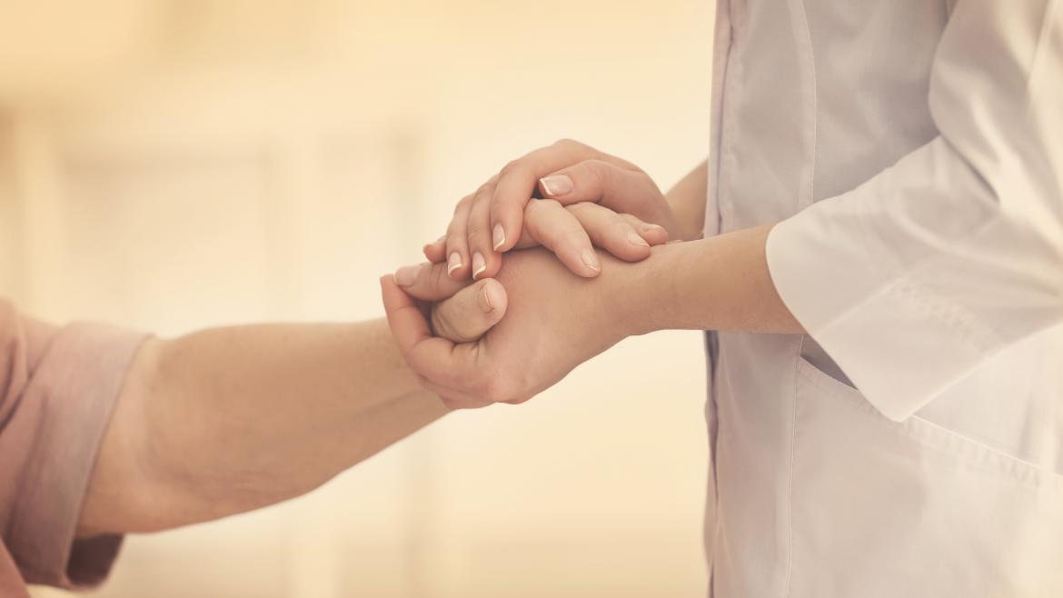 Una doctora coge las manos de una paciente