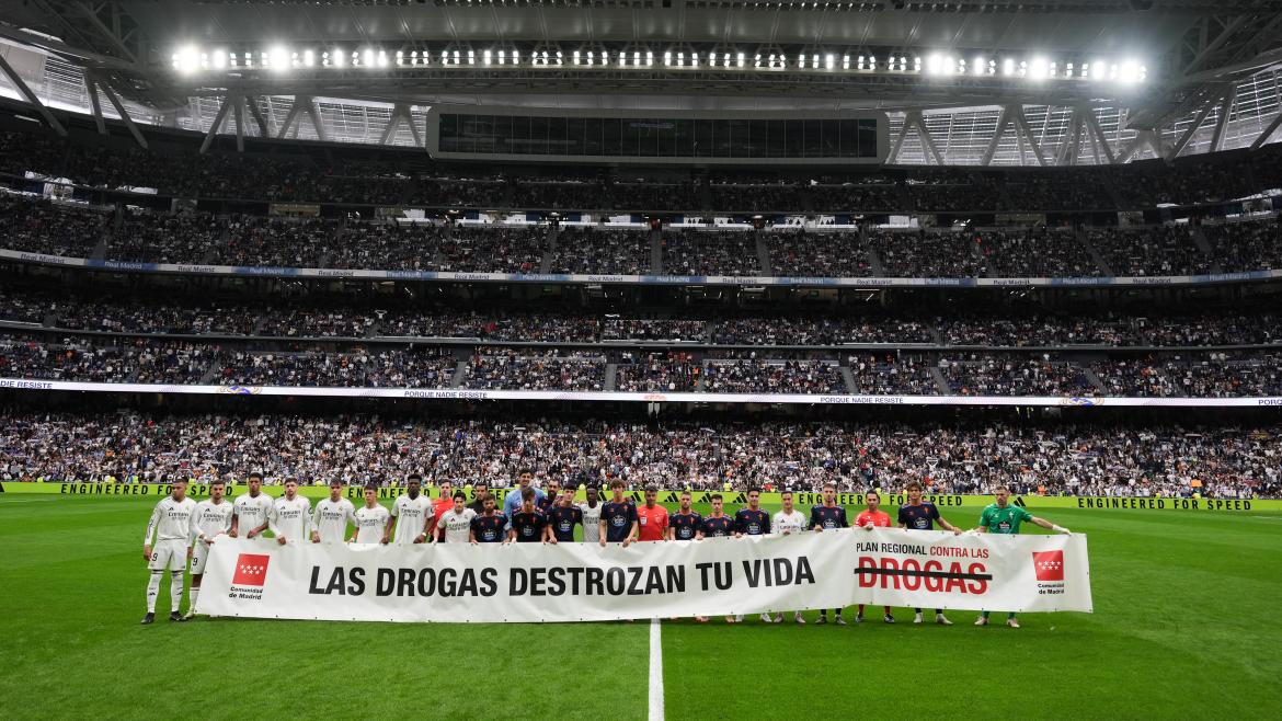 Jugadores de fútbol en el Santiago Bernabéu mostrando una pancarta del Plan Regional contra las Drogas 