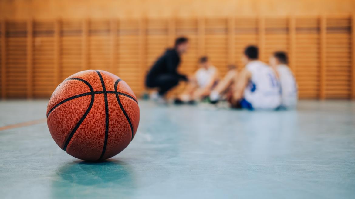 Pelota de baloncesto en la cancha con equipo al fondo