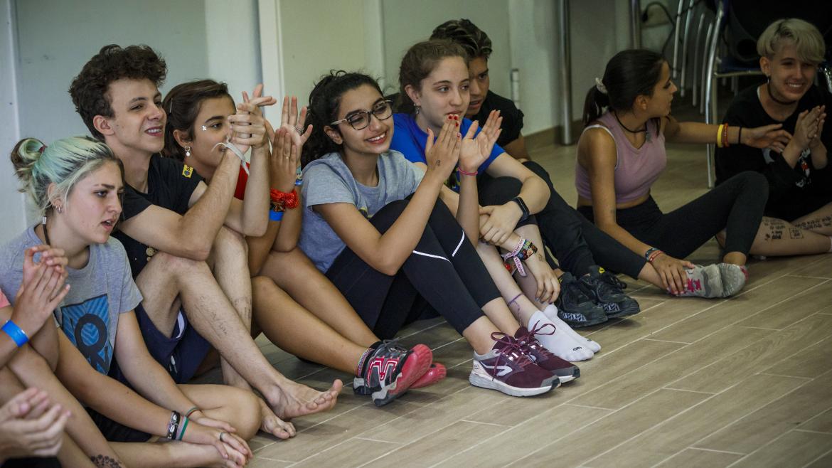 Jóvenes sentados en el suelo aplaudiendo