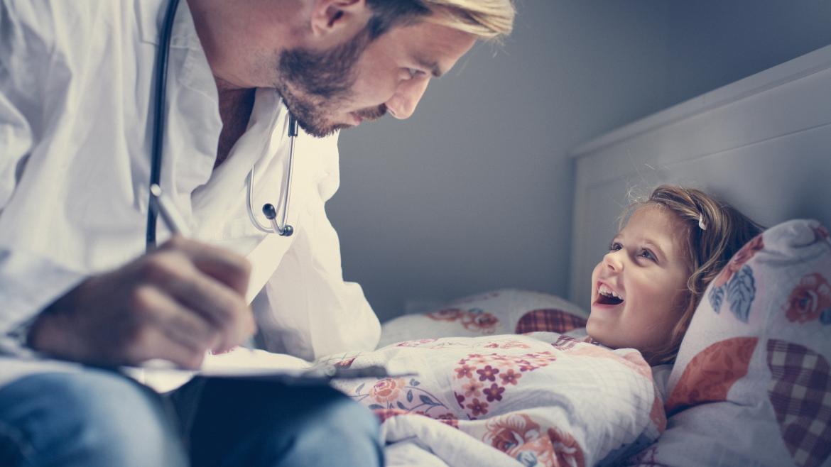 Médico atendiendo a niña en una cama de casa