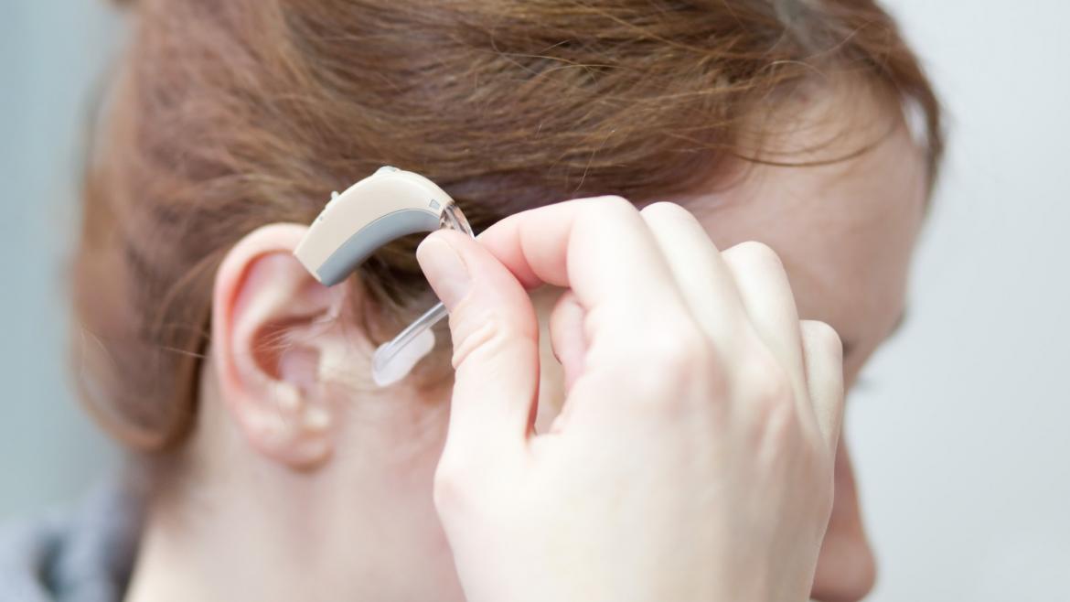 Primer plano de una mujer colocándose un audífono