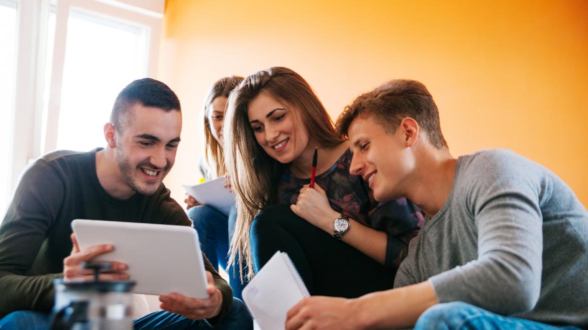 Un joven muestra a otros jovenes una tablet con algo que les hace felices