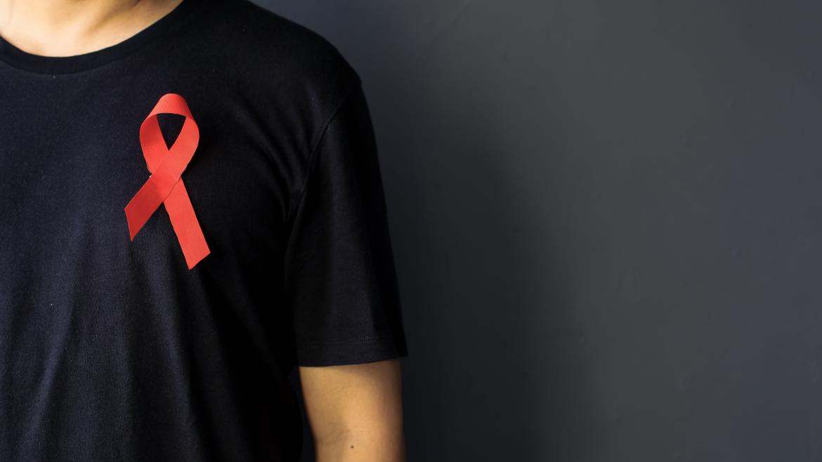 Hombre con camiseta negra con un lazo rojo