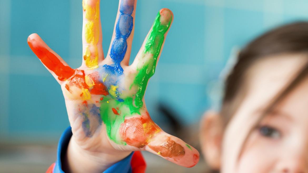 Niña en colegio con las manos de pintura 