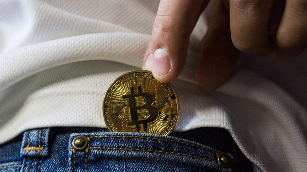 Criptomonedas Mano metiendo una moneda a un bolsillo de pantalón